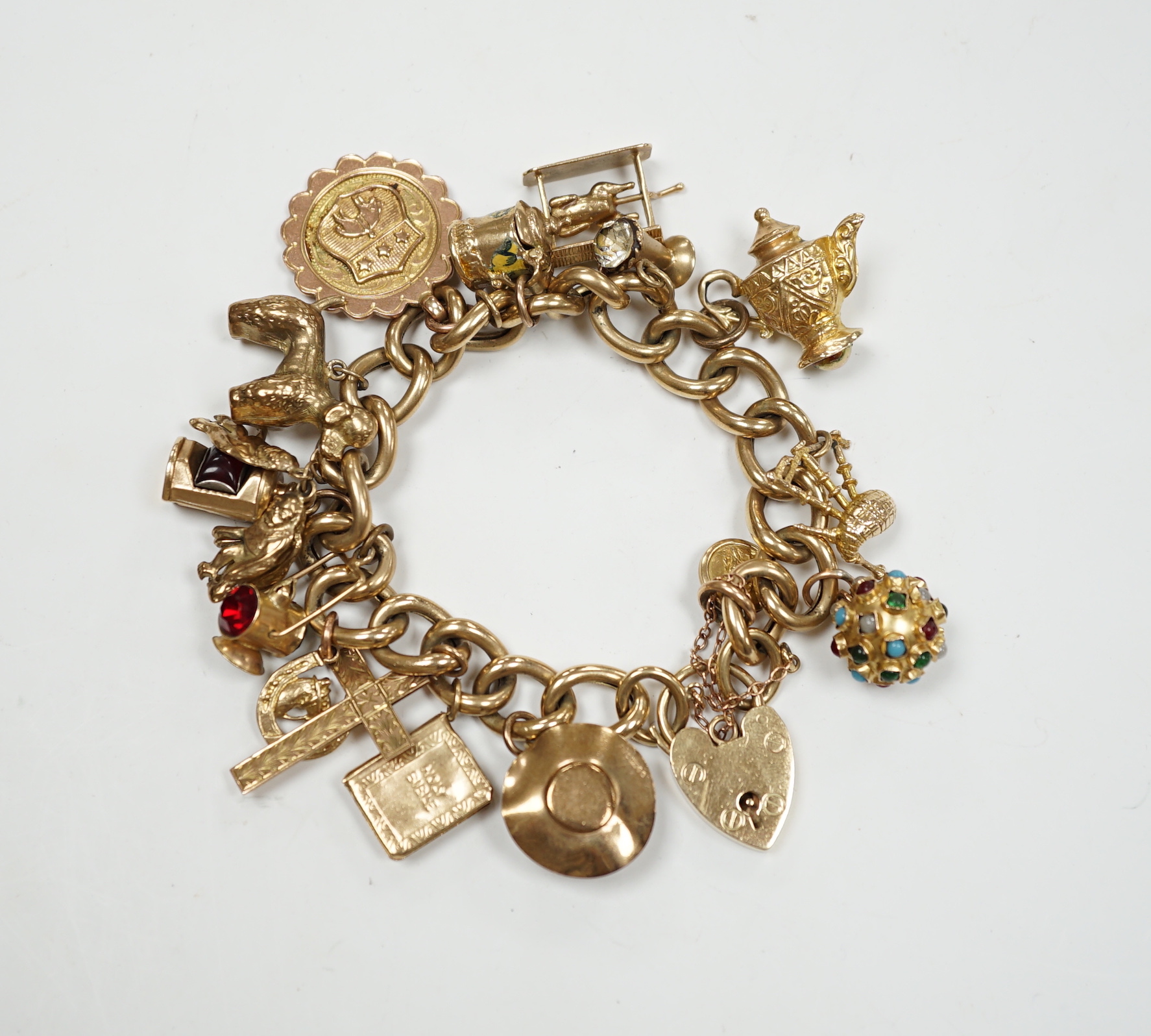 An early 1960's 9ct gold curb link charm bracelet, hung with fifteen assorted charms, including twelve 9ct gold, gross weight 49.7 grams.